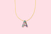 Colorful confetti letter necklace displayed flat on a pastel background.