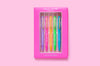 Five colorful motivational pens arranged inside a pink gift box on a solid pink background.