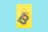 Confetti letter B acrylic keychain on a yellow backer card with gold keyring
