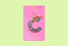 Confetti letter C acrylic keychain on a green backer card with gold keyring