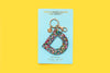 Confetti letter D acrylic keychain on a yellow backer card with gold keyring