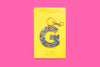 Confetti letter G acrylic keychain on a pink backer card with gold keyring