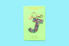 Confetti letter J acrylic keychain on a teal backer card with gold keyring