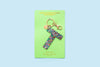 Confetti letter K acrylic keychain on a green backer card with gold keyring