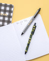 Taylor Elliott gel pens resting on notebook with gingham stationery