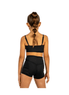 Young dancer wearing black V-waist dance shorts with coordinating top, standing facing forward.