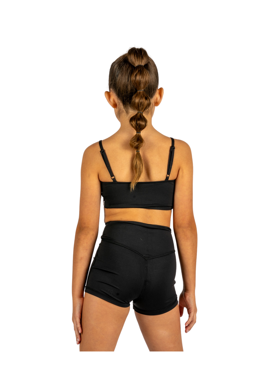 Young dancer wearing black V-waist dance shorts with coordinating top, standing facing forward.