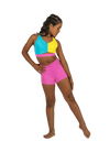 Young dancer wearing pink V-waist dance shorts with a colorful crop top, standing in a studio pose.