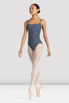 Young dancer wearing a black camisole leotard standing en pointe against a neutral background