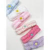 Assorted pastel spa headbands with daisy flower details displayed in a row