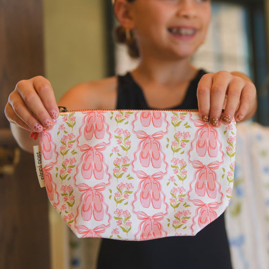 Person holding a pink pouch with ballet slipper design