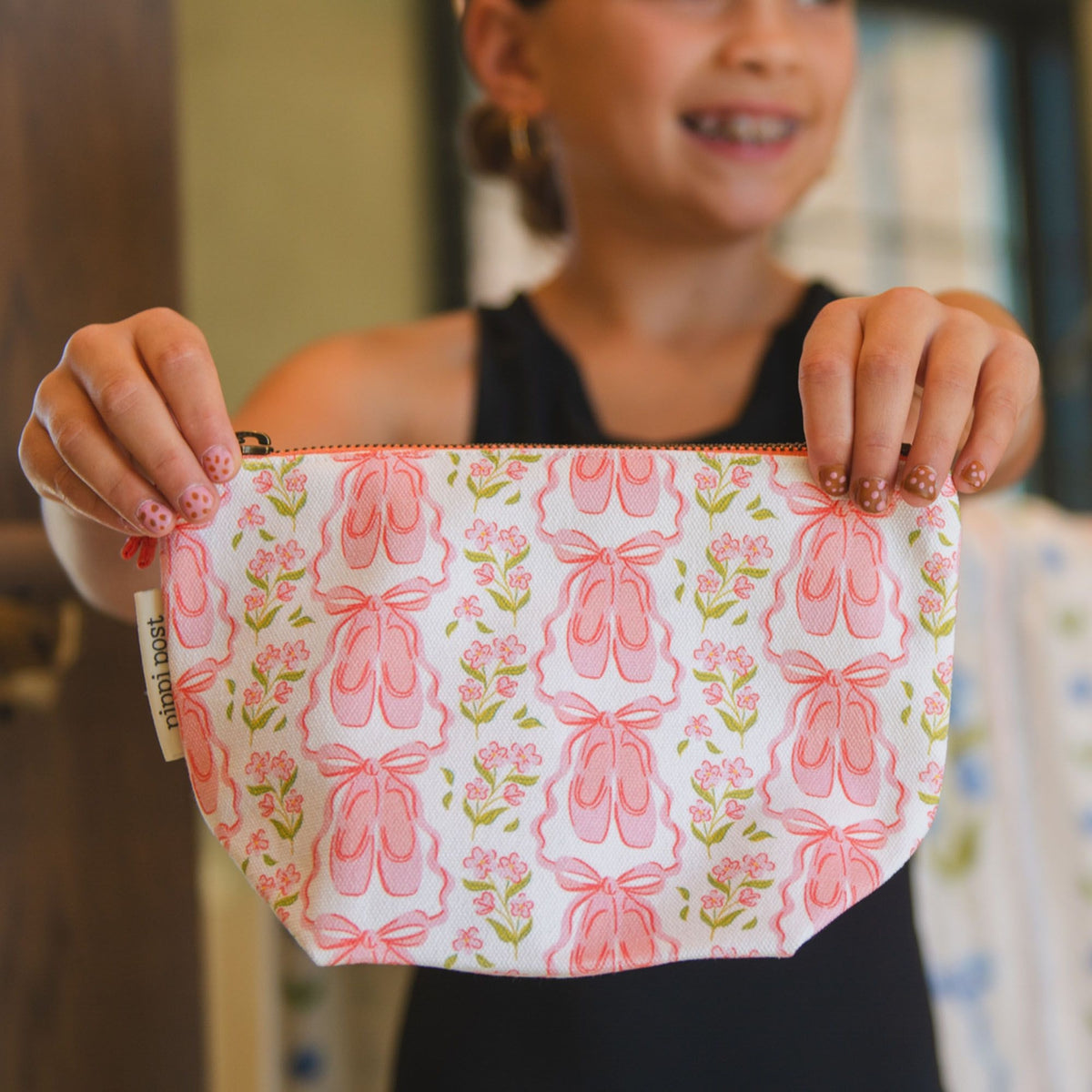 Person holding a pink pouch with ballet slipper design