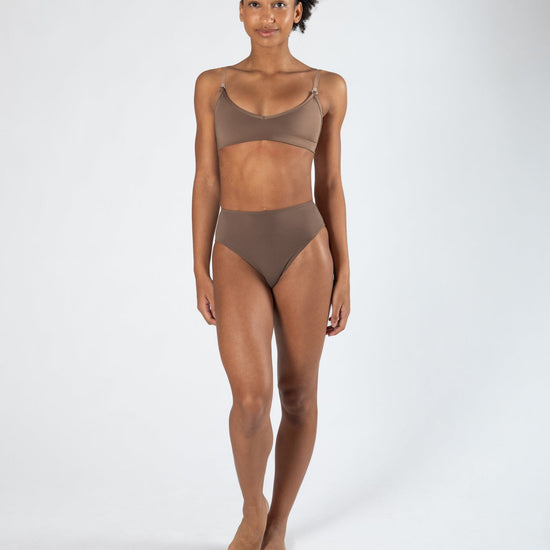 Model wearing a darker-toned high cut dance brief with matching bra, front view