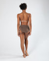 Model wearing a darker-toned high cut dance brief with matching bra, back view