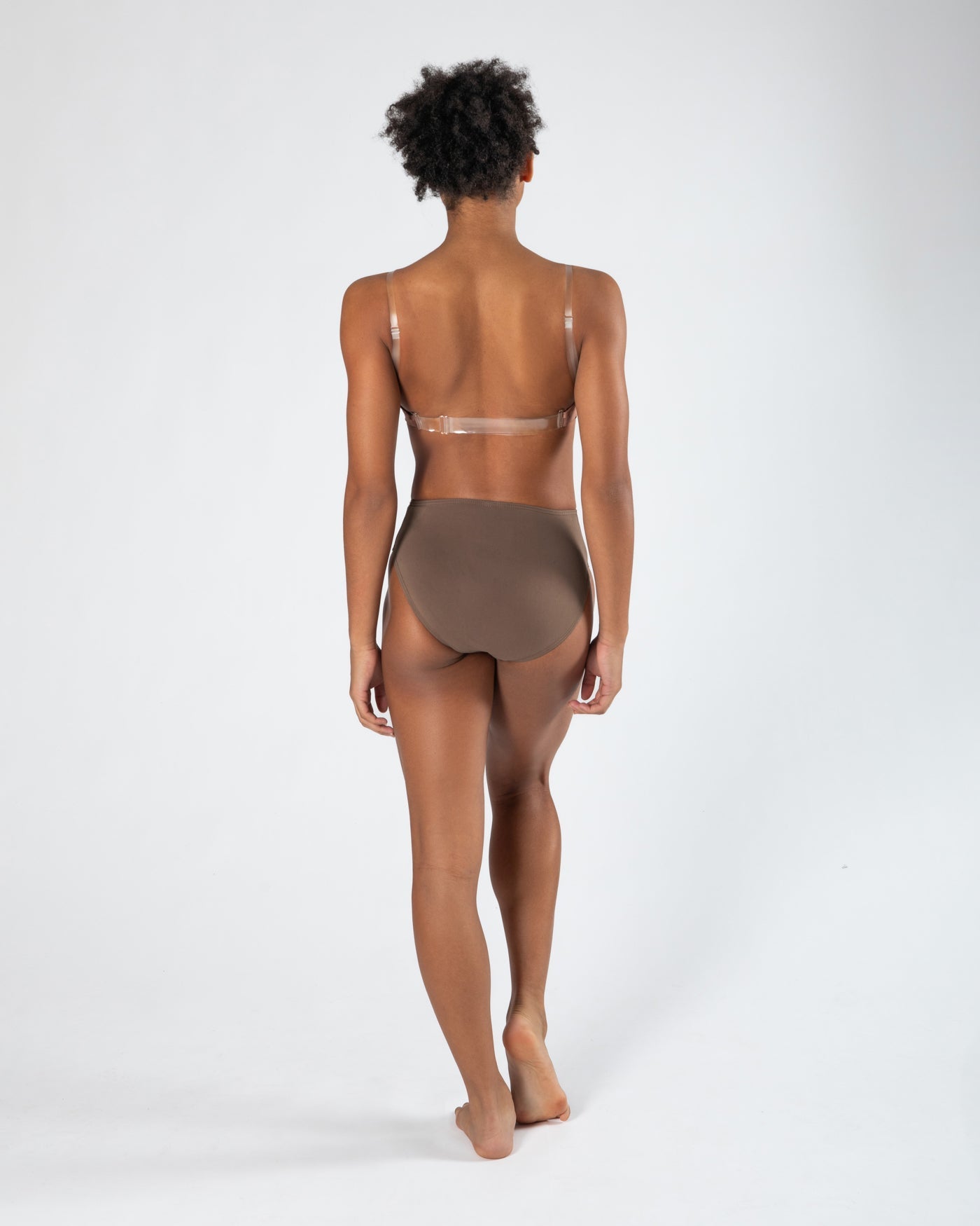 Model wearing a darker-toned high cut dance brief with matching bra, back view