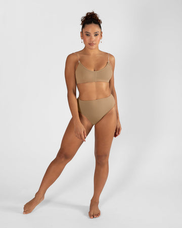 Model wearing a nude high cut dance brief with matching bra, front view