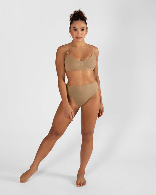 Model wearing a nude high cut dance brief with matching bra, front view