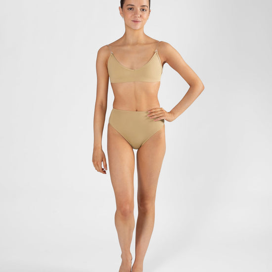 Full body front view of model wearing nude high cut dance brief and matching bra