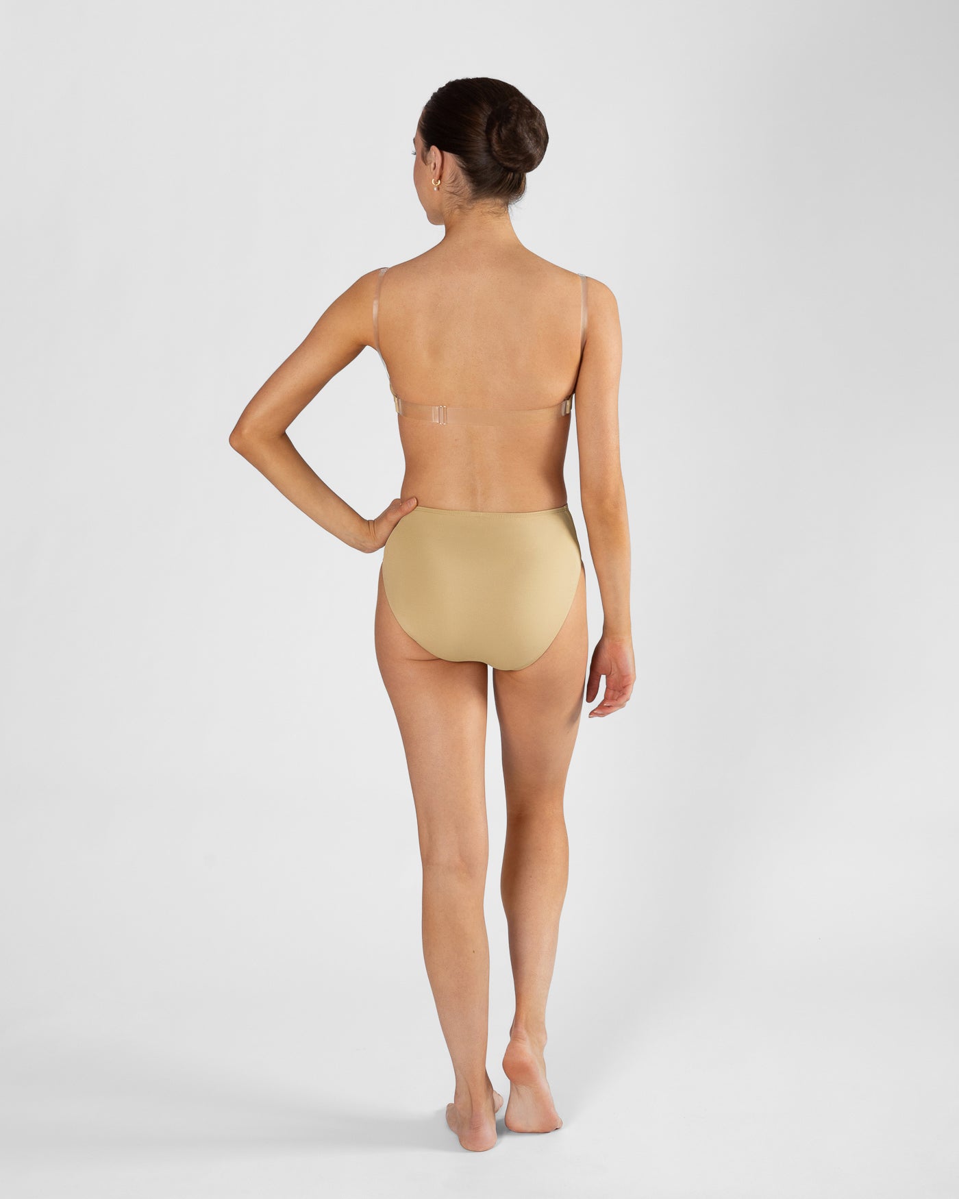 Full body back view of model wearing nude high cut dance brief and matching bra