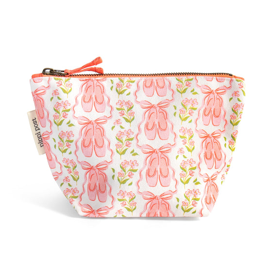 A small zippered pouch with a white background and an all-over print of pink ballet shoes, pink flowers, and green leaves. The pouch has a peach zipper and pull, and a fabric tag on the left side that reads 'Peach Pouch'.