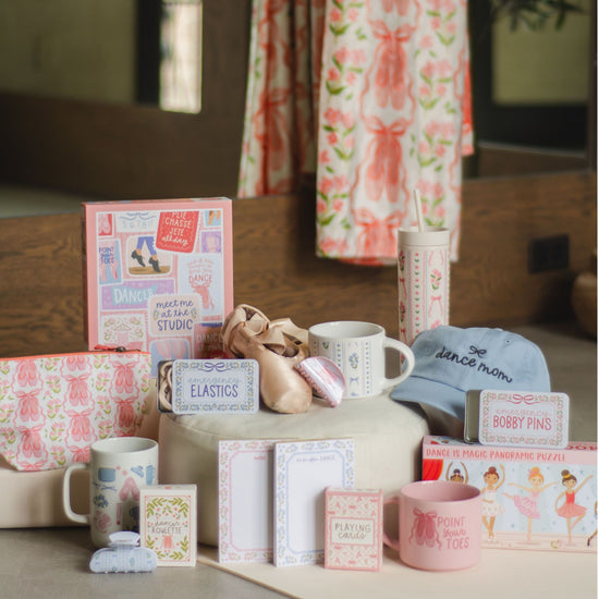 Collection of items including mugs, boxes, and a hat on a surface with a floral curtain in the background.