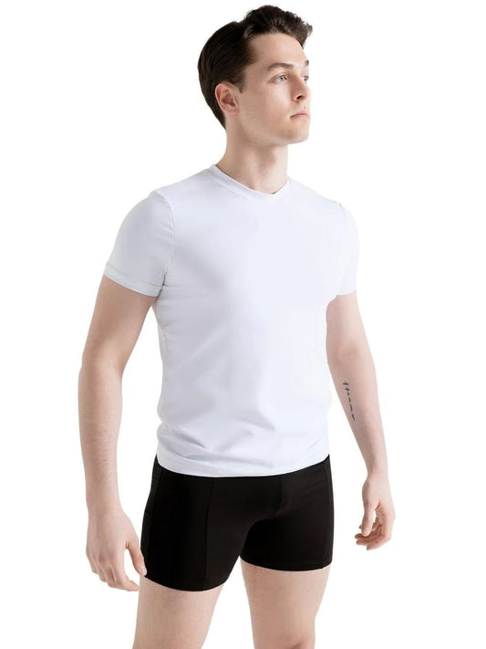 Male dancer wearing black fitted dance shorts and a white shirt standing against a white background
