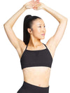 Adult dancer wearing a black strappy bra top with front mesh detail, shown from the front with arms raised