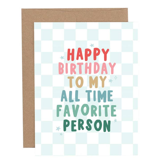 Birthday greeting card with the phrase “Happy Birthday to My All Time Favorite Person” in colorful lettering on a light blue checkered background, shown with a brown envelope.