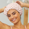 Model wearing a terracotta checker shower cap, smiling with hair fully covered