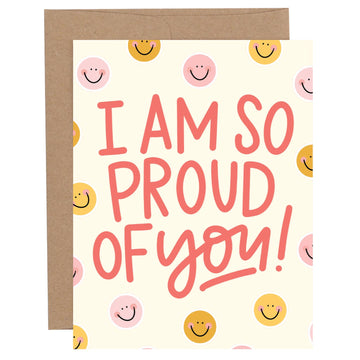 Pippi Post So Proud Smiley congratulations greeting card with colorful smiley faces, coral hand-lettered message, and kraft envelope