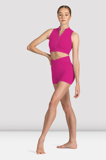 Dancer wearing a bright pink zip front crop top with matching shorts standing against a neutral background
