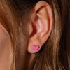 Close-up of a pink heart stud earring worn in an ear.
