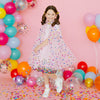 Young girl wearing pink confetti cape at a colorful birthday celebration