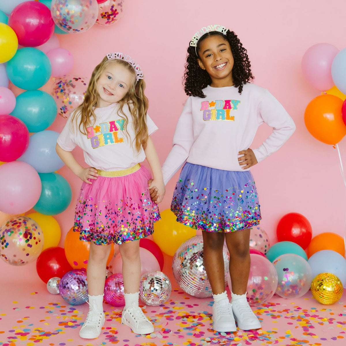 Two children wearing colorful confetti tutu outfits with party decorations