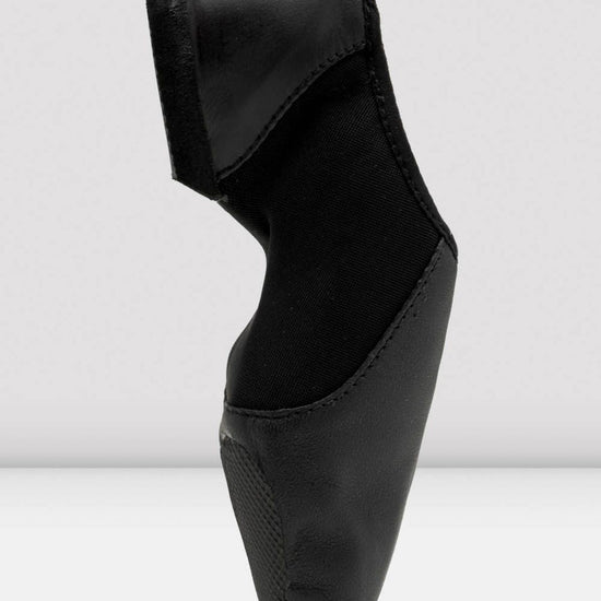 Side profile of a black slip-on leather jazz shoe standing upright.
