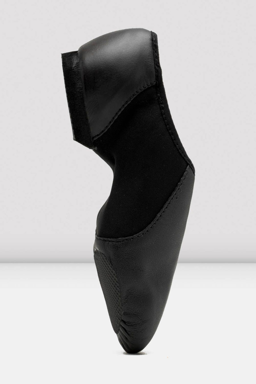 Side profile of a black slip-on leather jazz shoe standing upright.