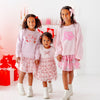 Three girls wearing coordinating pink outfits and bow accessories