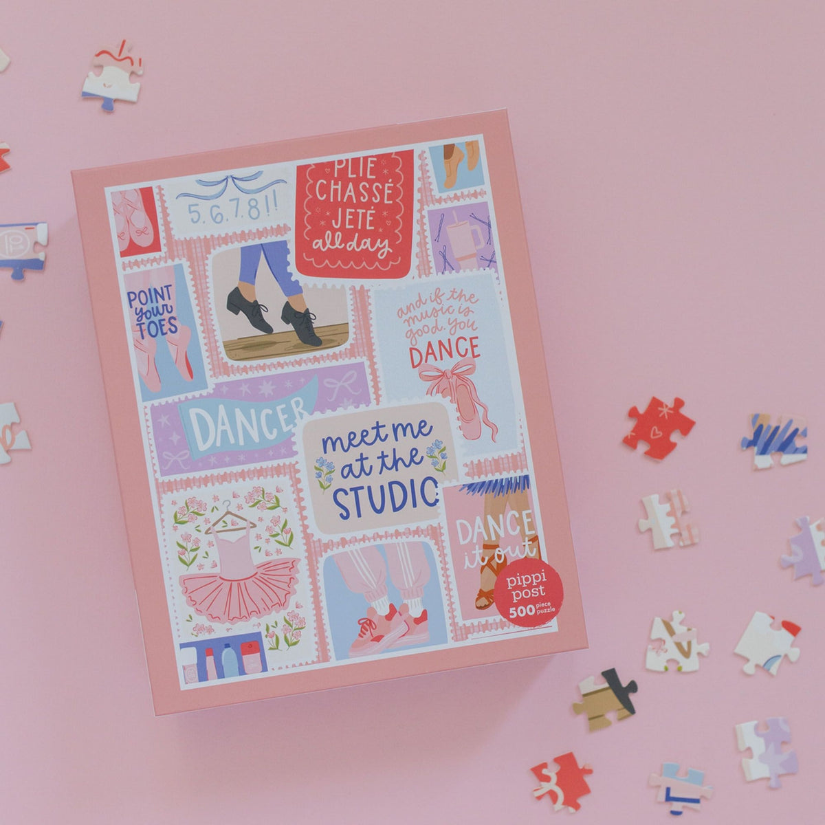 A pink puzzle box with colorful ballet-themed illustrations and scattered jigsaw puzzle pieces on a light pink background. The box reads 'PIE CHASSE JETE everyday' and 'meet me at the STUDIO'.