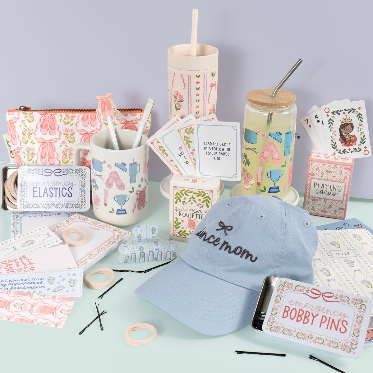 Collection of stationery items including a blue cap, hair accessories, and stationery products on a light green surface.