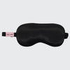 Black satin eye mask shown laid flat with adjustable elastic strap visible
