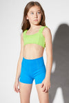 Dancer wearing a lime green layout-style dance top paired with bright blue high-waisted shorts