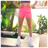 Model wearing neon pink high-waisted dance shorts outdoors.