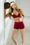Adult dancer wearing a red zip-front dance bra with matching bottoms, standing indoors.