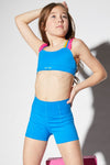 Dancer wearing a sonic blue dance top with plush elastic straps and matching shorts